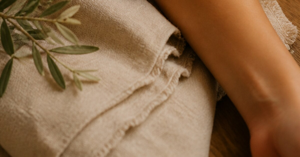 A calm body massage setting with warm linen and botanical branches