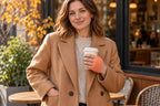 One hand tucked into a coat pocket and the other wearing a warmer while holding coffee.