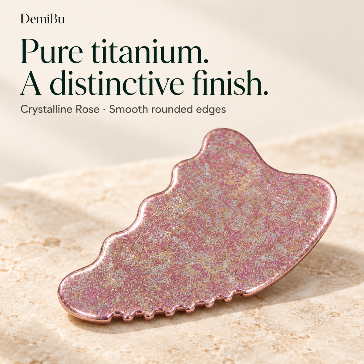 A close view of the Crystalline Rose titanium gua sha showing its reflective rose-pink finish and contoured edges