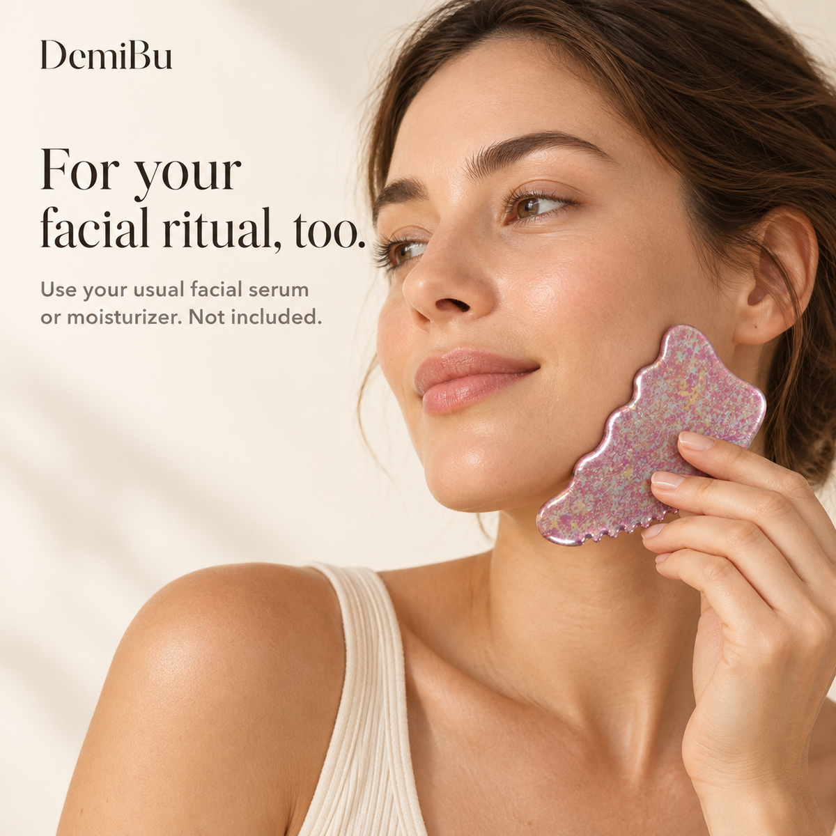 An adult woman gently holding the Crystalline Rose titanium gua sha along her jawline for a separate facial-care routine
