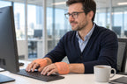 An adult typing at a computer with warmers on the backs of both hands and fingers uncovered.