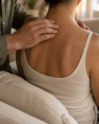 One adult gently massaging another adult’s shoulders at home, with no faces shown.