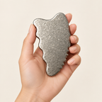 Crystalline Silver titanium gua sha held in one hand to show its compact scale