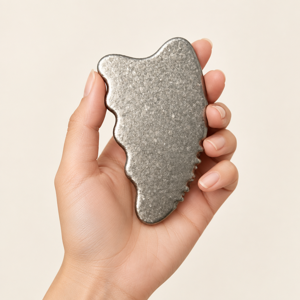 Crystalline Silver titanium gua sha held in one hand to show its compact scale