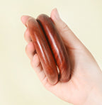Two wooden five-tooth combs held in one palm showing thickness